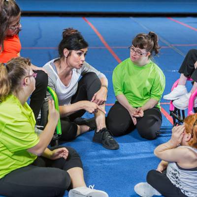 woman talking with special education students on a gymnastics floor