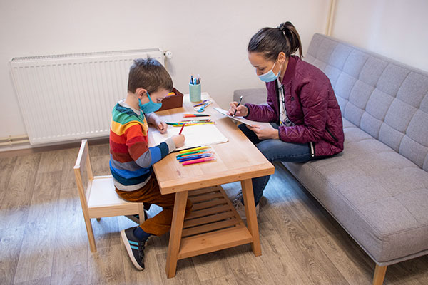woman taking notes while child is drawing