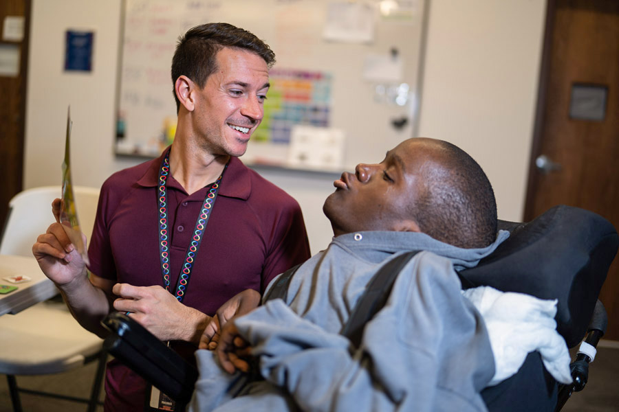 severely disabled student of color in a wheelchair learning from an instructor