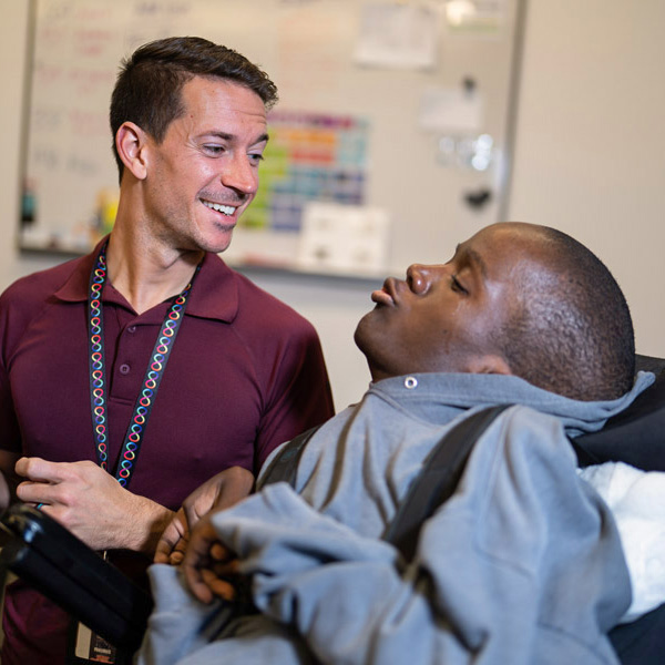 severely disabled student of color in a wheelchair learning from an instructor