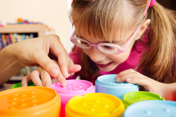 visually impaired student doing an activity with guidance from a teacher