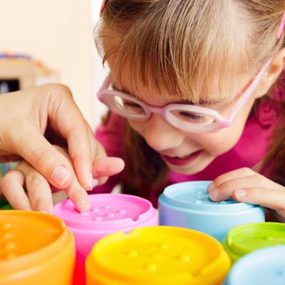visually impaired student doing an activity with guidance from a teacher